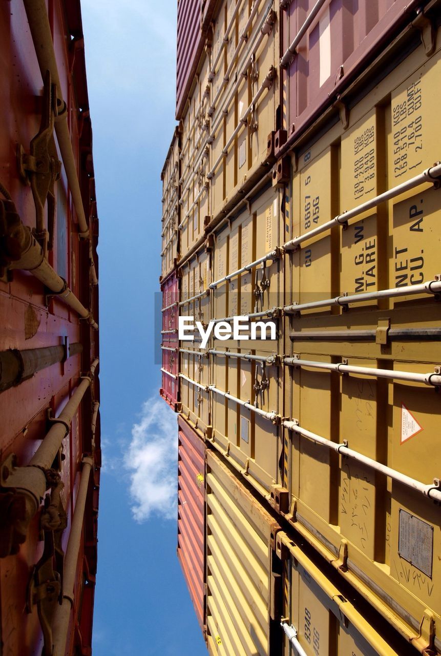 Low angle view of cargo containers in harbor against sky