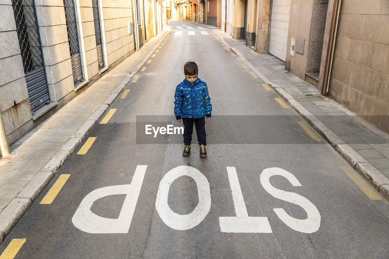 Boy standing by stop text on road