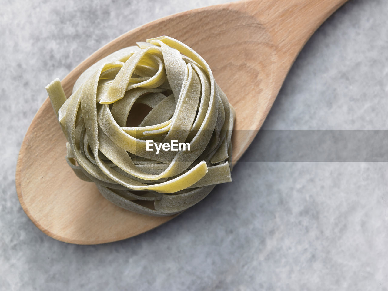High angle view of tagliatelle pasta on wooden spoon at table