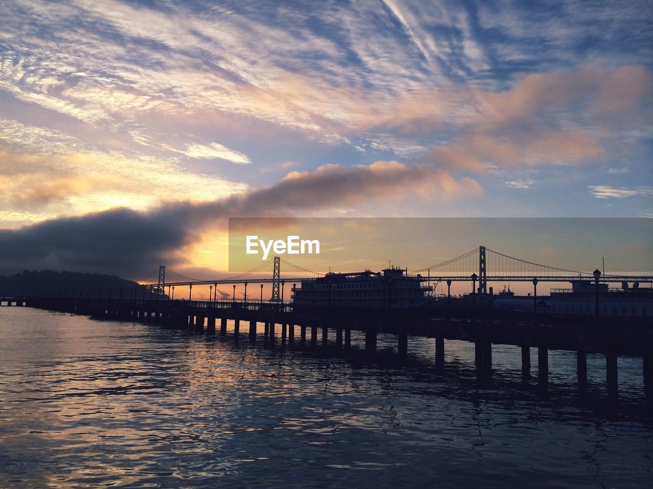 Scenic view of silhouette bridges against cloudy sky during sunset