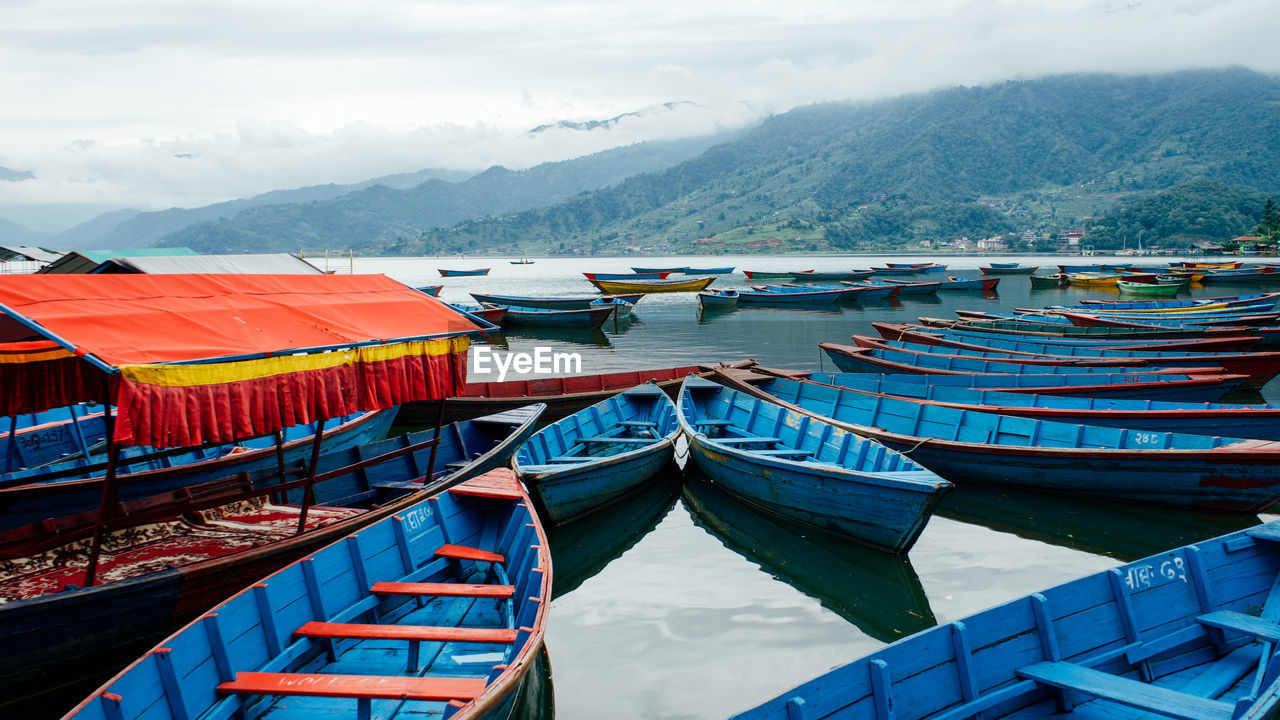 Boats moored in lake against mountains