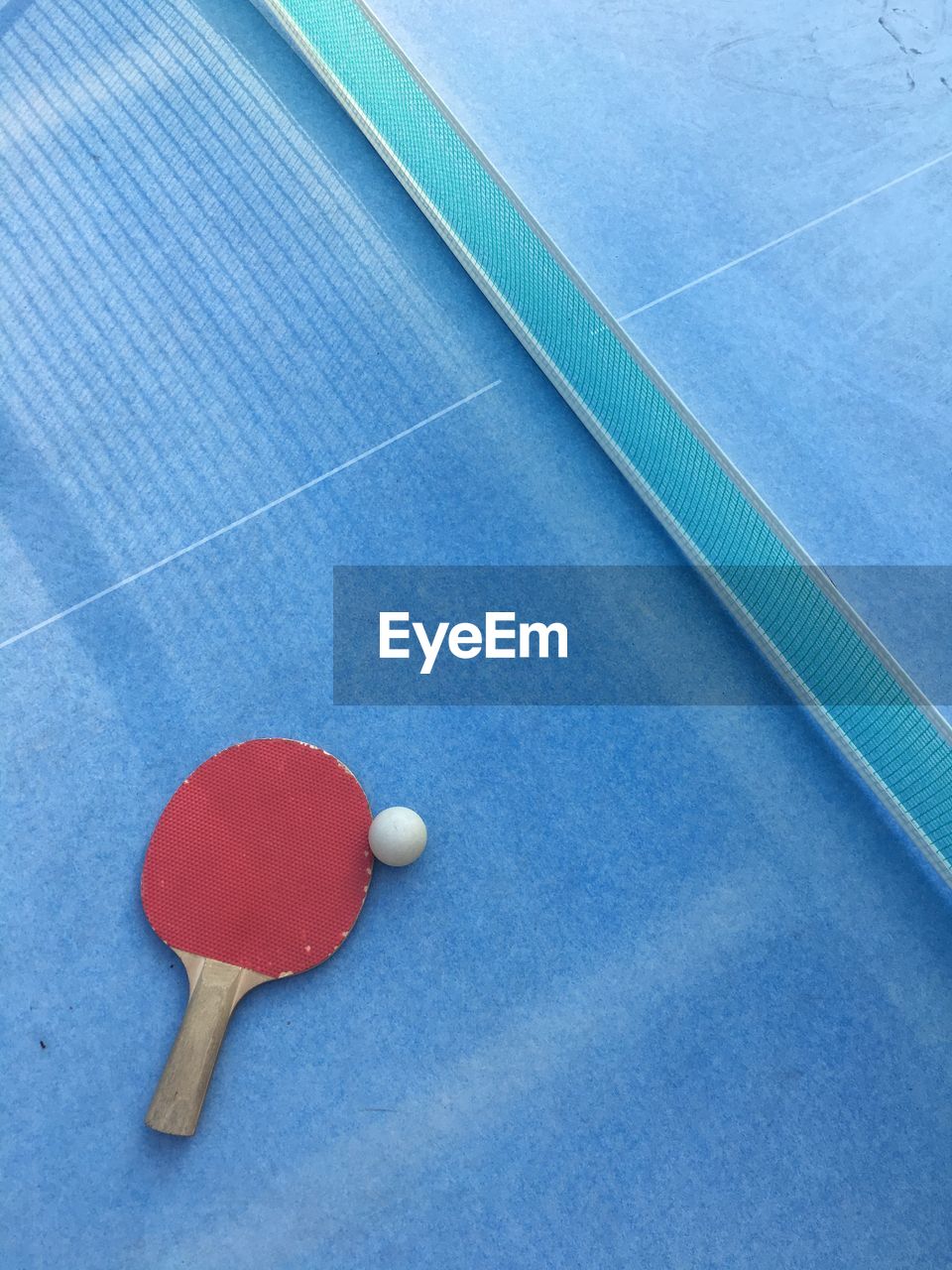 High angle view of table tennis racket with ball by net