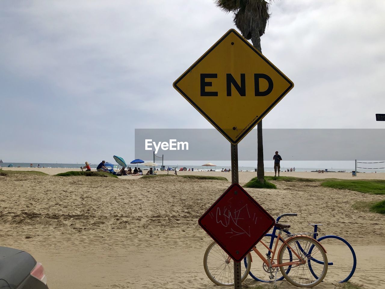 Information sign on road by beach against sky