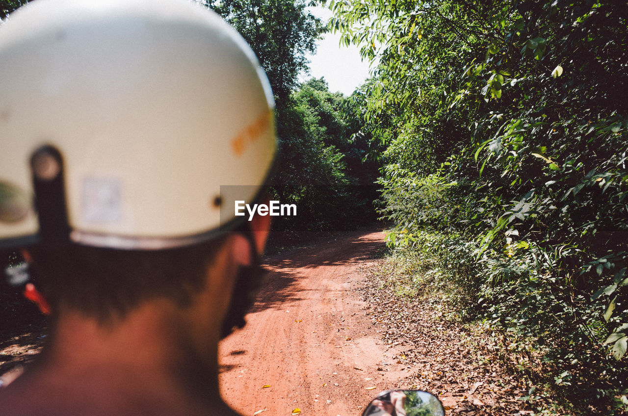 Man wearing helmet while riding motorcycle on dirt road