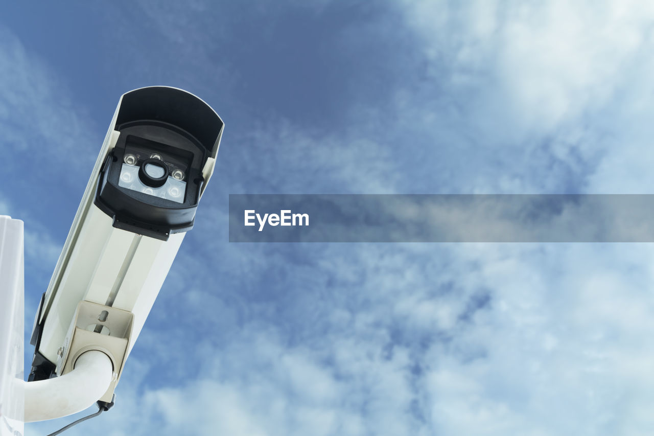 Low angle view of security camera against blue sky