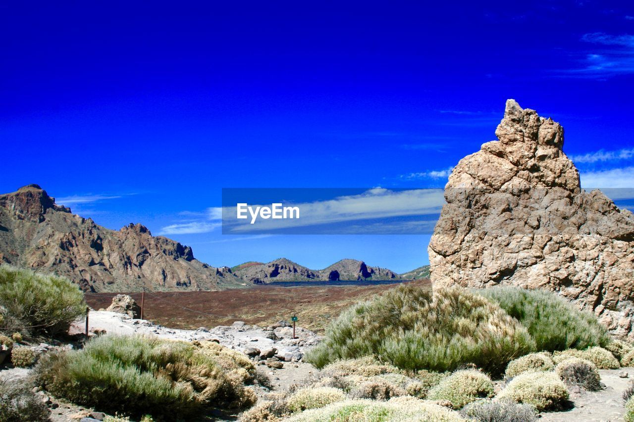 Rock formations on landscape against blue sky