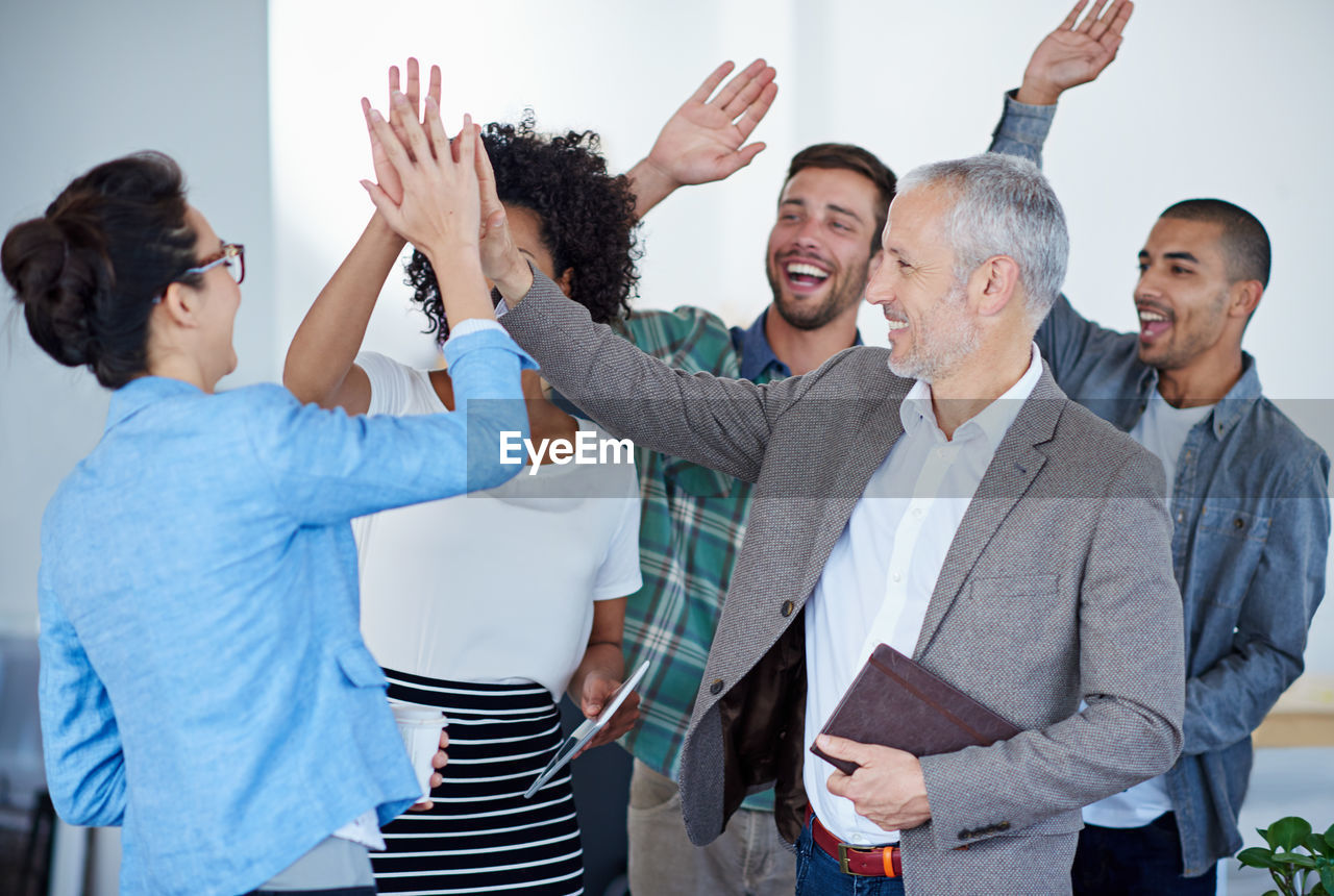 Business colleagues doing high five in office