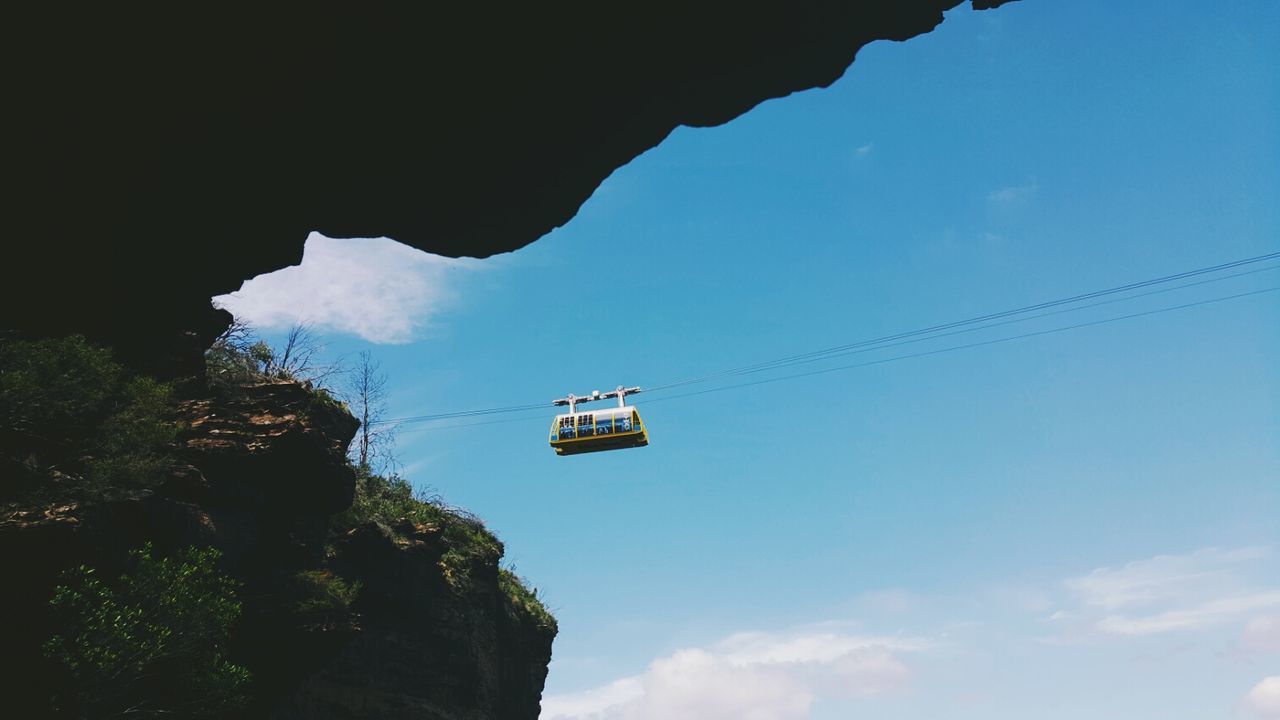 Low angle view of overhead cable car against sky