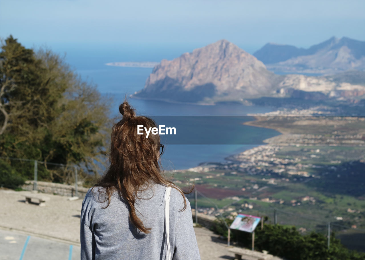 Rear view of woman with hair bun standing against mountains