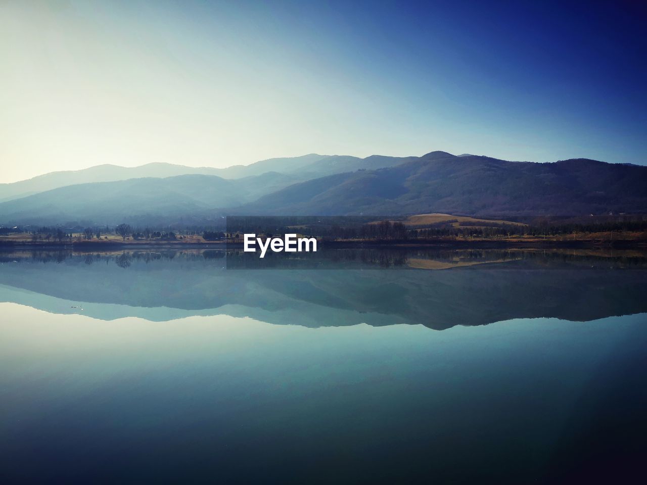 Scenic view of lake and mountains against sky the perfect reflection of the sky and mountains.. 