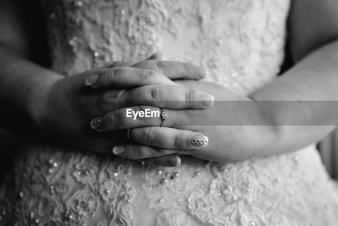 Midsection of bride with hands clasped during wedding ceremony