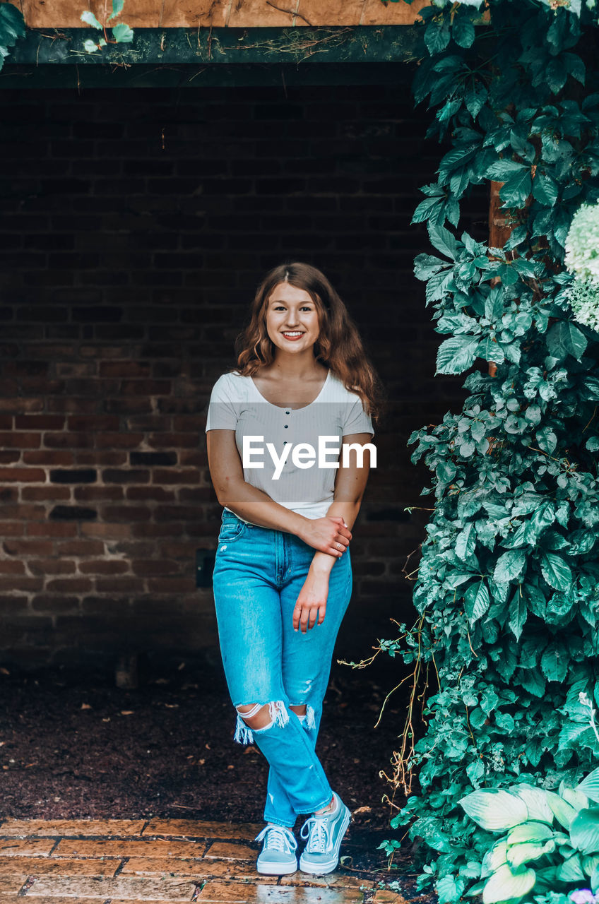 Portrait of smiling girl standing against brick wall