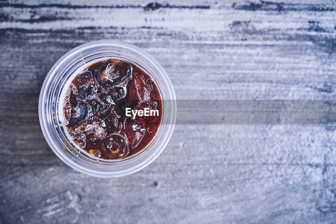 Directly above shot of cola in disposable glass on table