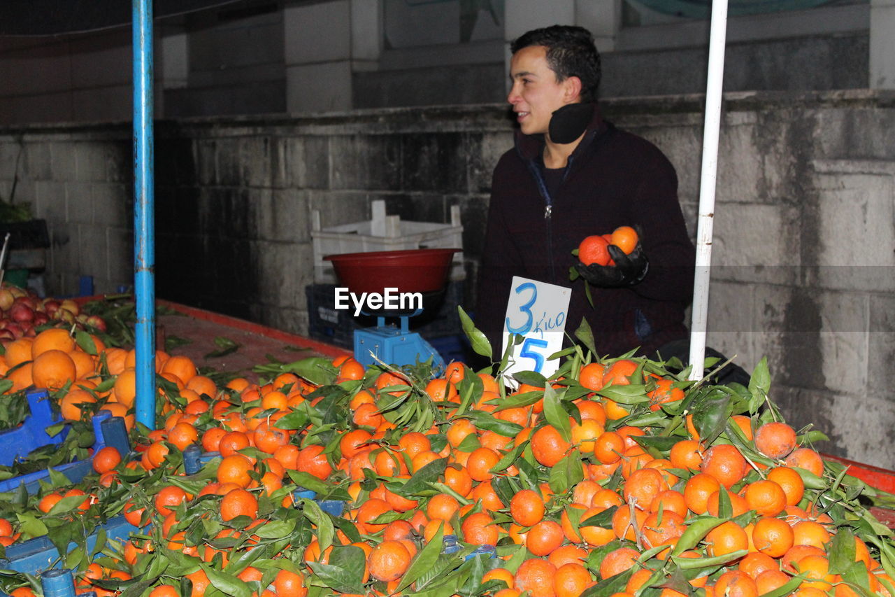 MAN STANDING BY FRUITS AT MARKET STALL