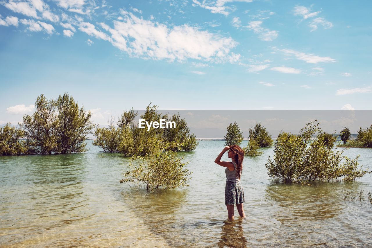 Woman standing in river against sky