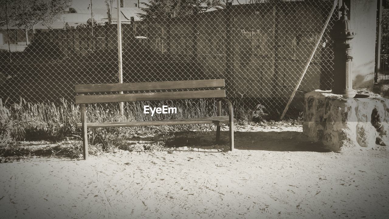 Empty bench against the fence