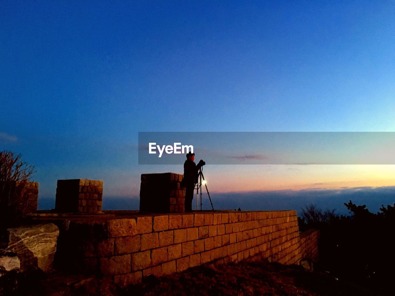 Side view of man photographing at sunset