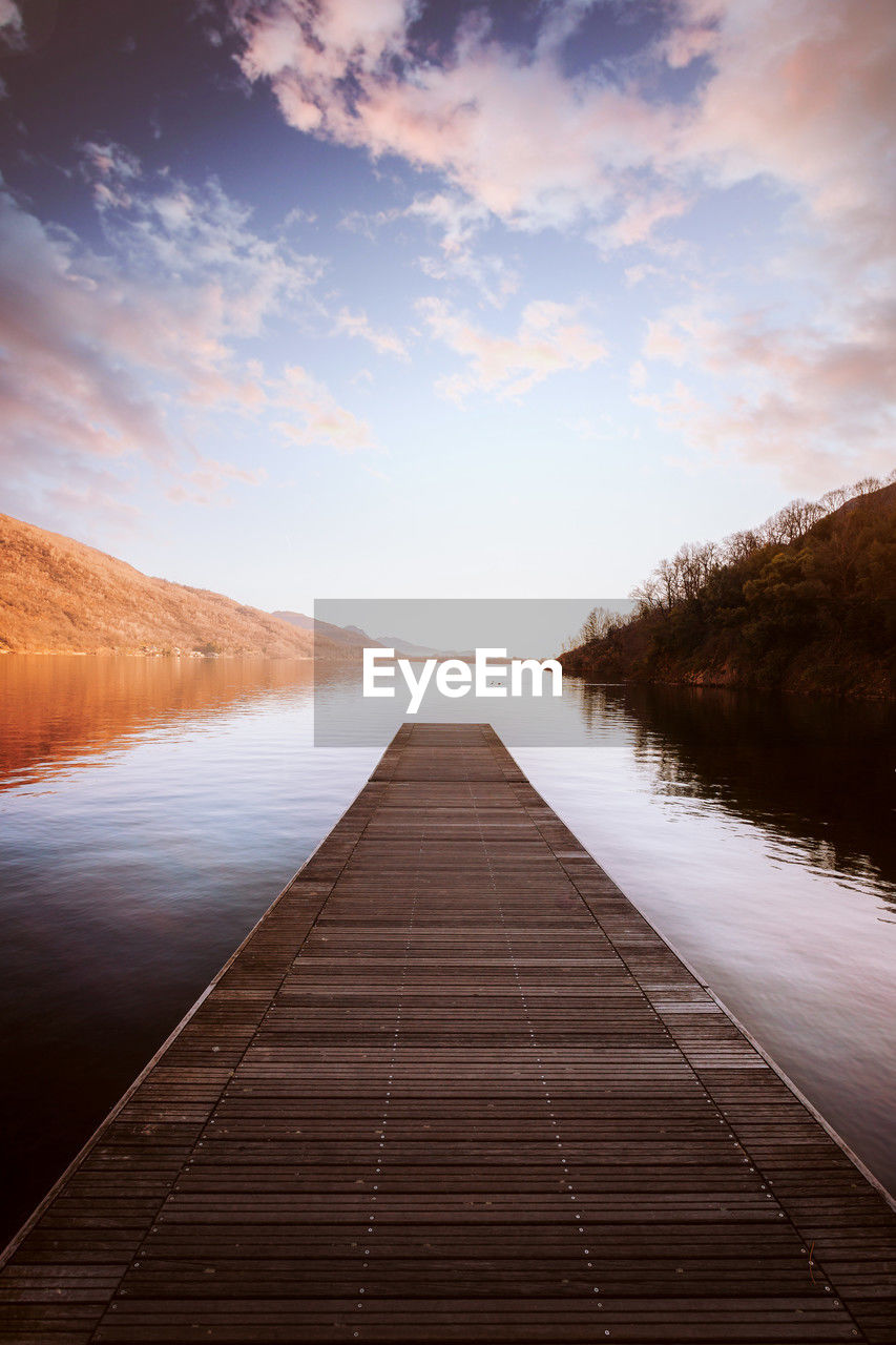 pier on lake against sky during sunset