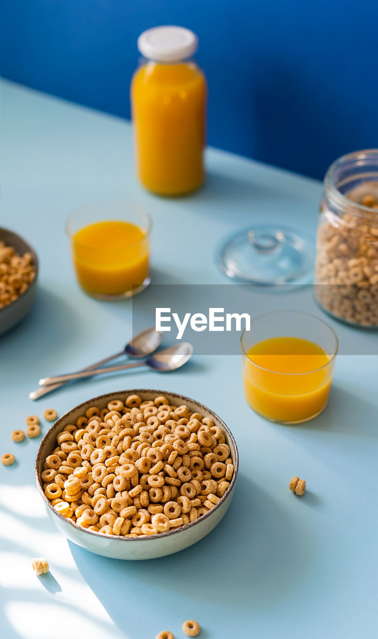 Breakfast concept with cold cereals and orange juice on blue background