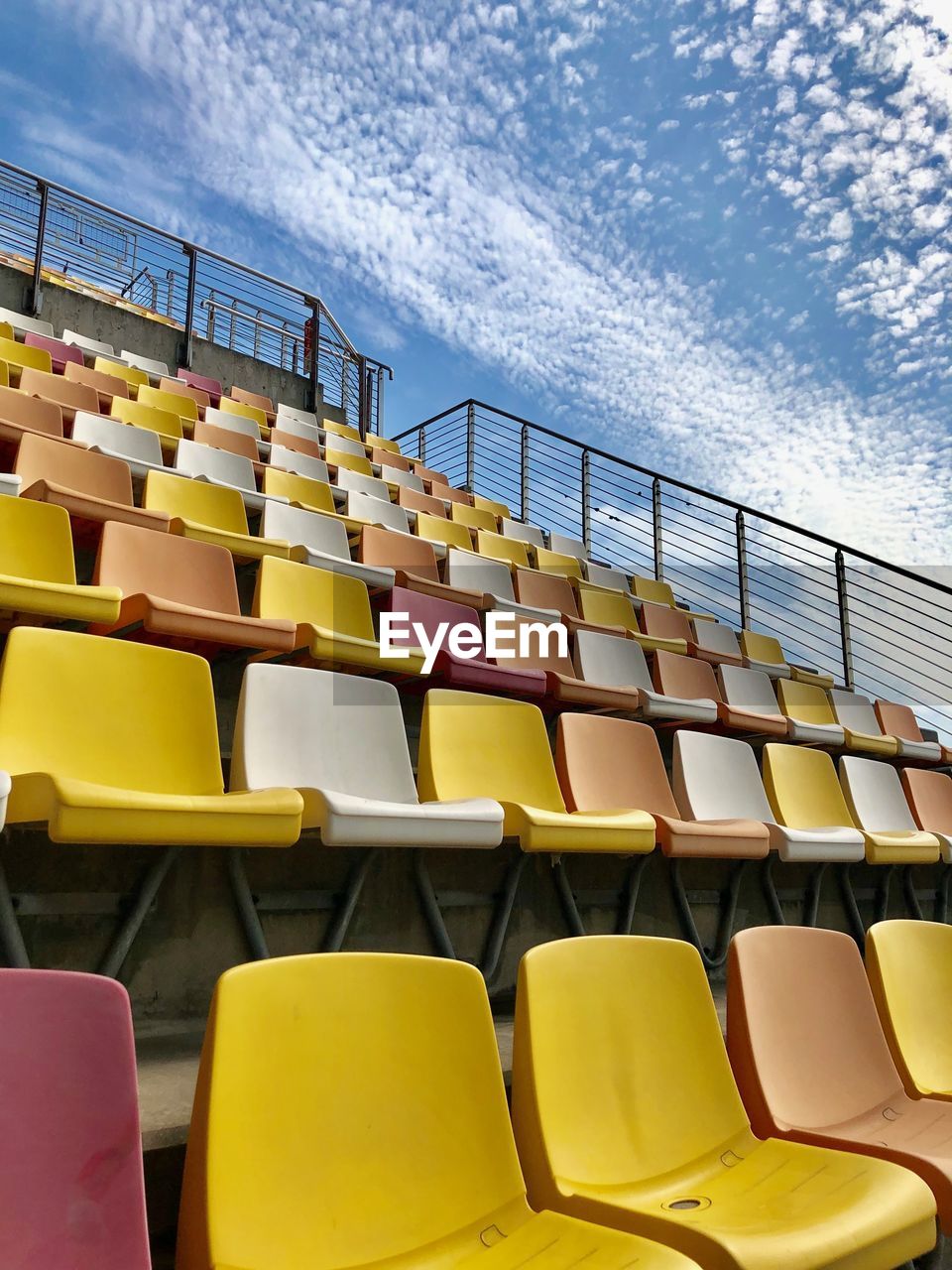 Empty chairs in stadium against sky