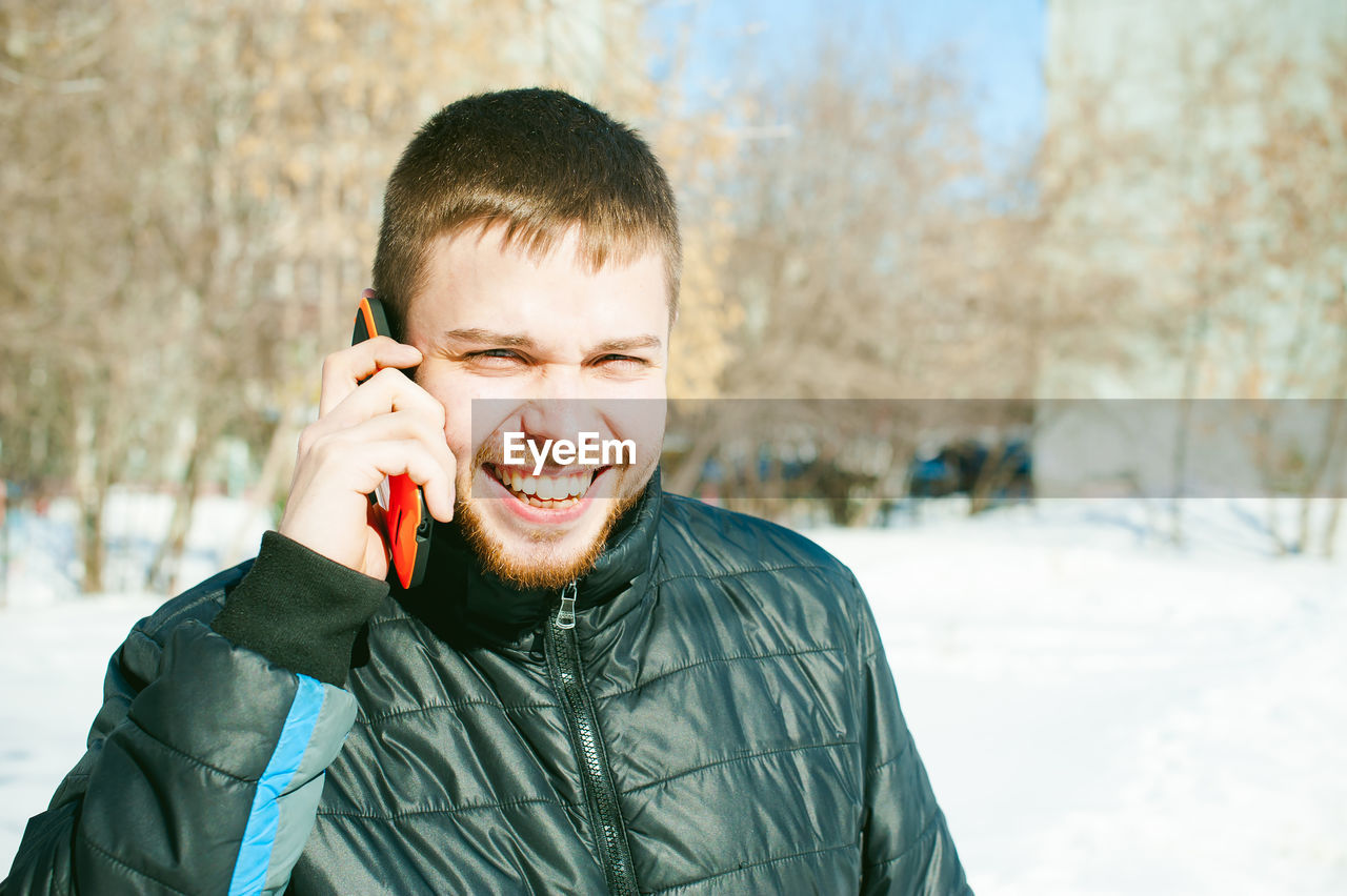 Portrait of smiling man in warm clothing talking on mobile phone
