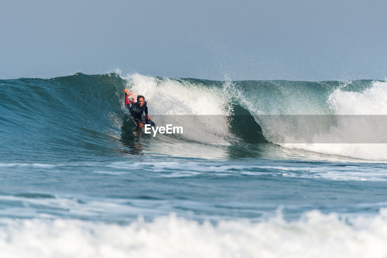 man surfing in sea against clear sky