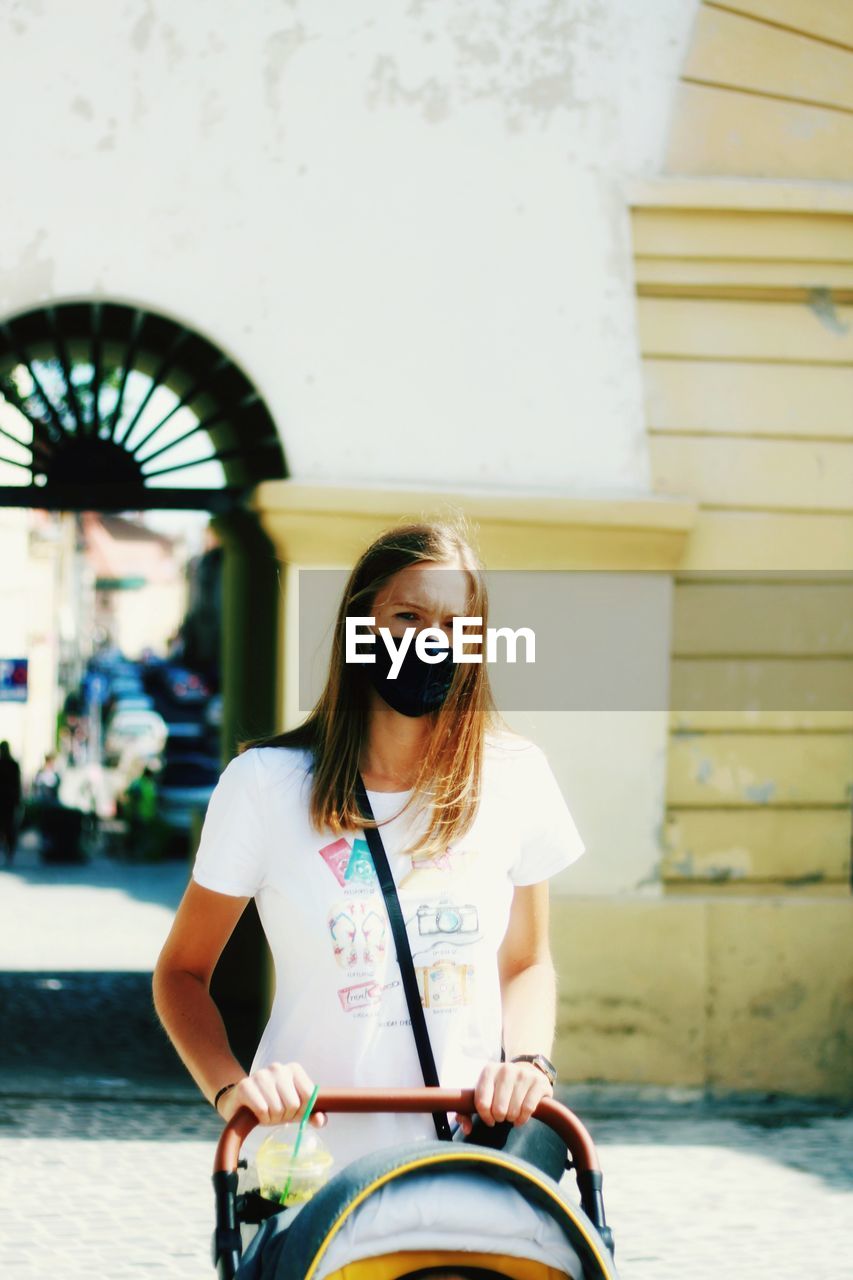 Portrait of young woman with coronavirus mask walking on the street