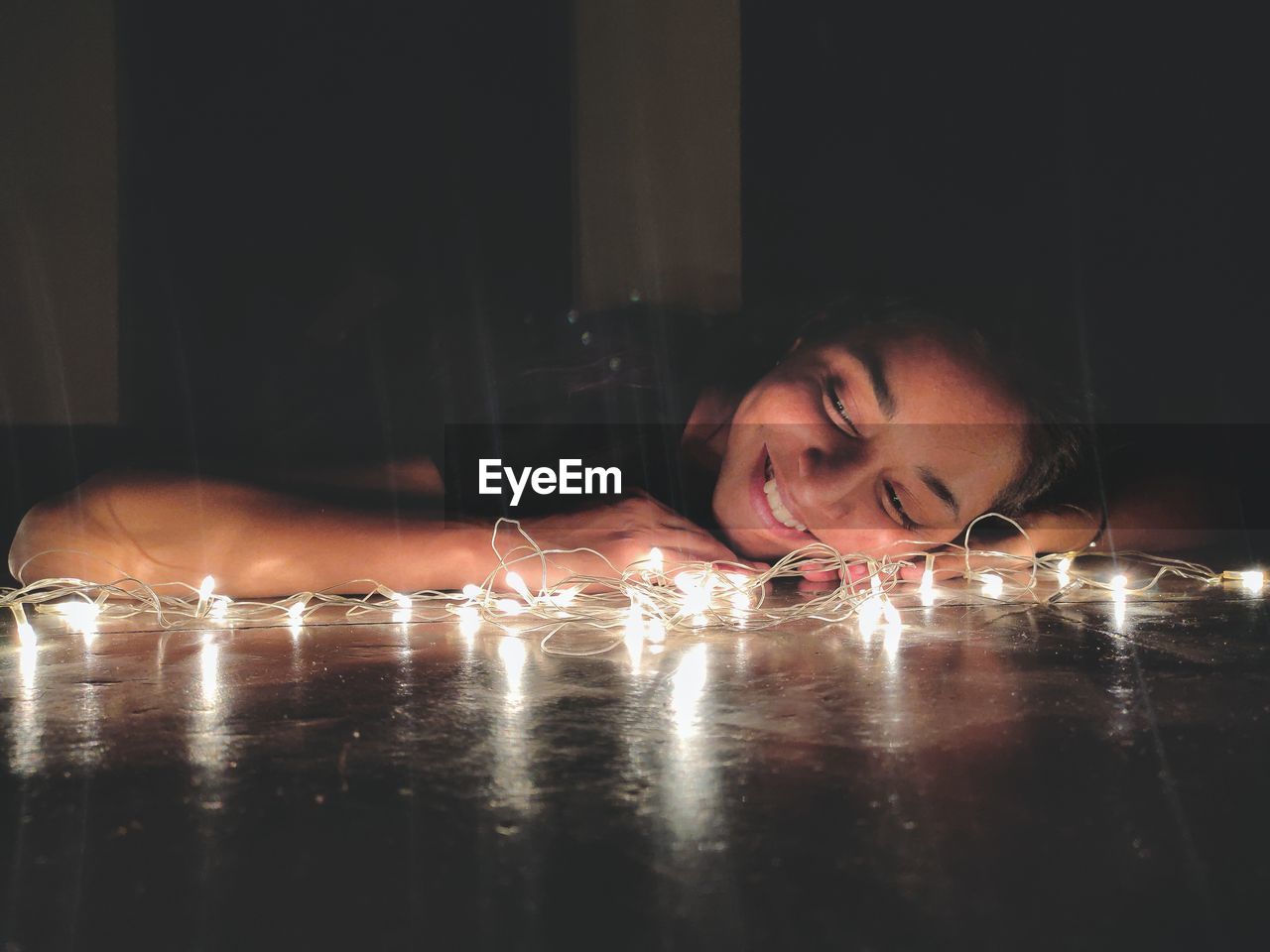 Portrait of girl lying down on table with fairy lights