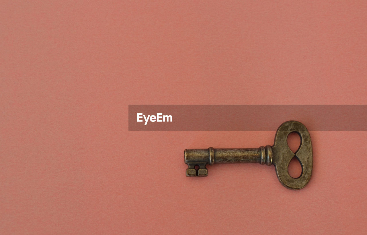 Lonely small old key on pink background