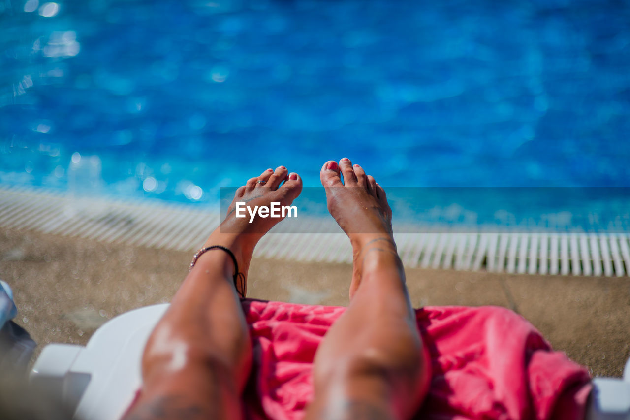 Low section of woman relaxing in swimming pool