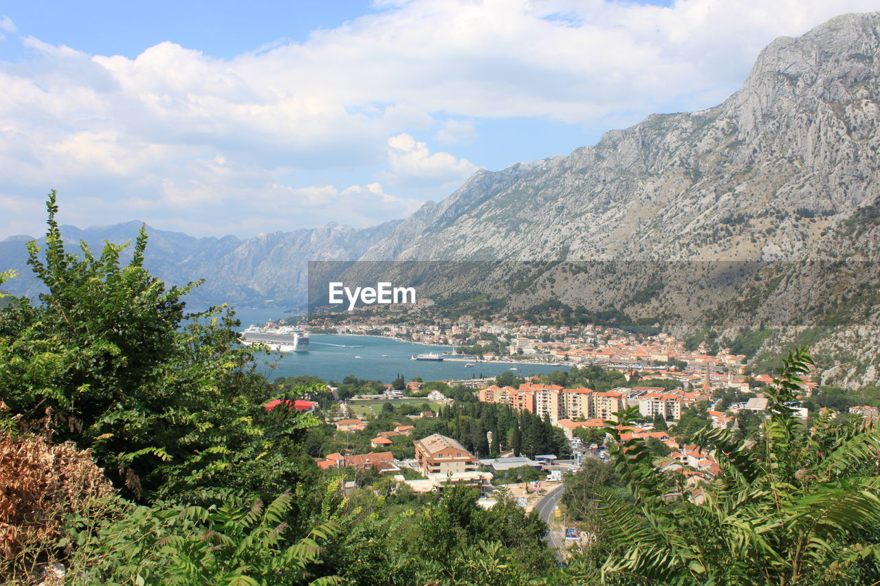 Scenic view of townscape by mountains against sky