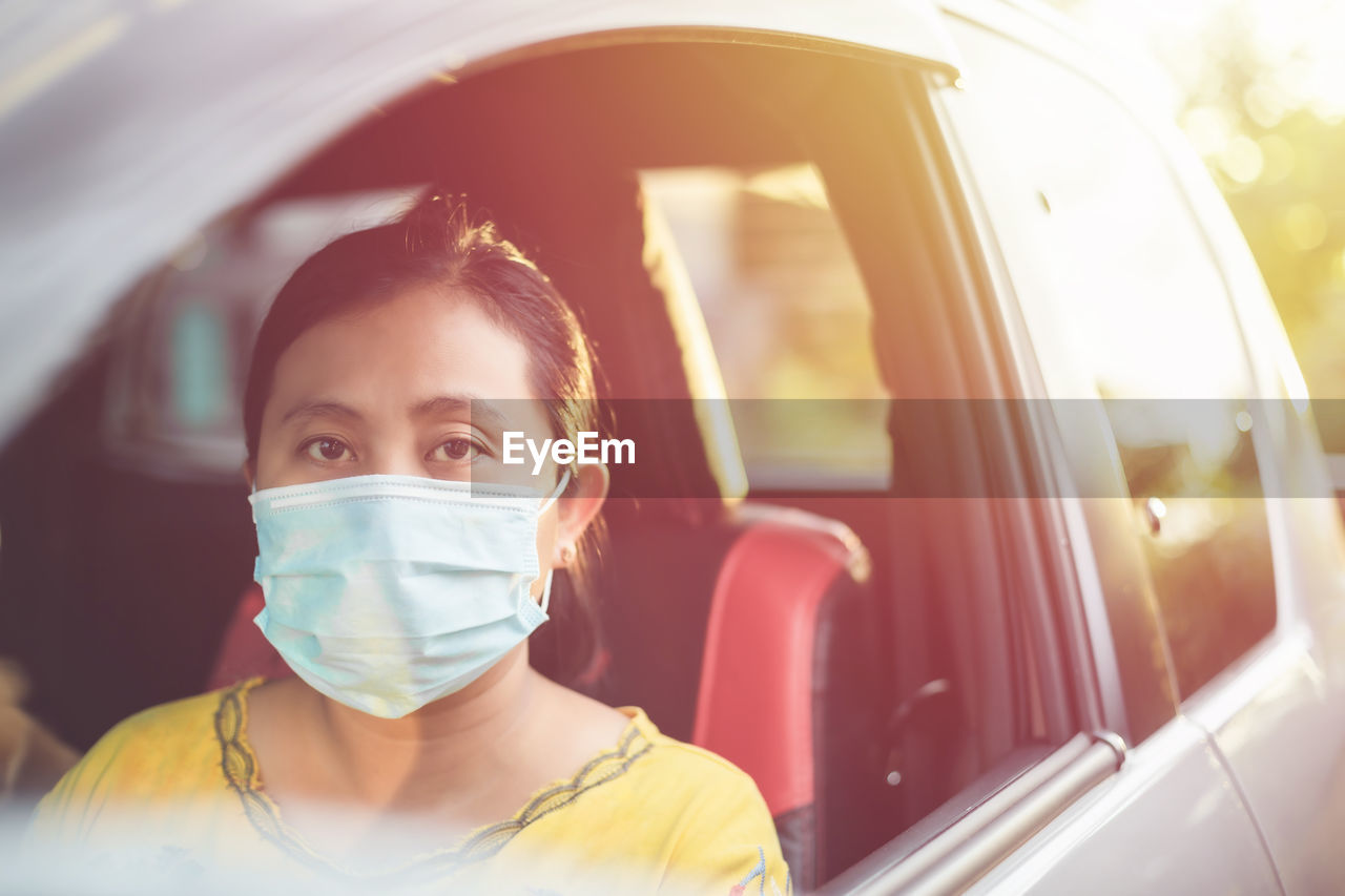 Asian woman wearing protective face mask and sitting in the private car. 