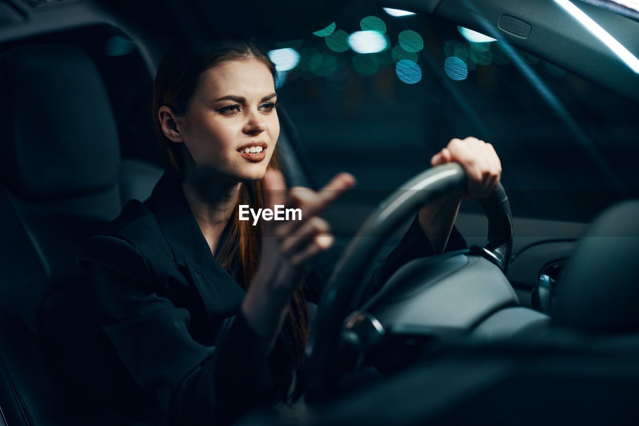 Smiling woman gesturing while sitting in car