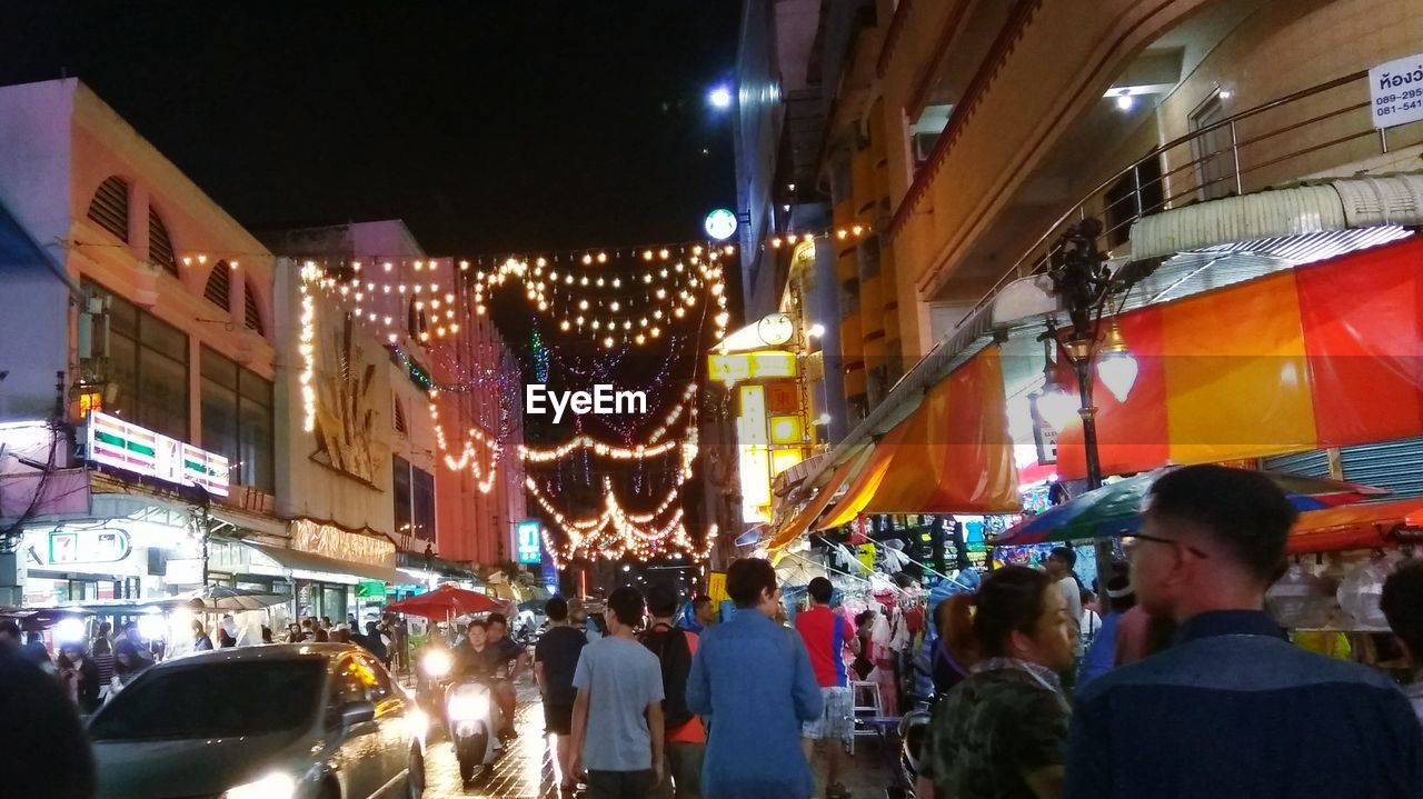 CROWD ON ILLUMINATED MARKET AT NIGHT