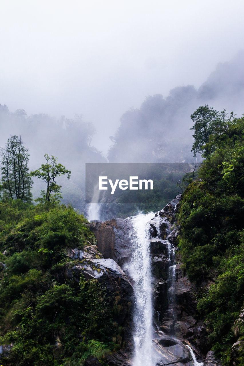 Scenic view of waterfall during foggy weather