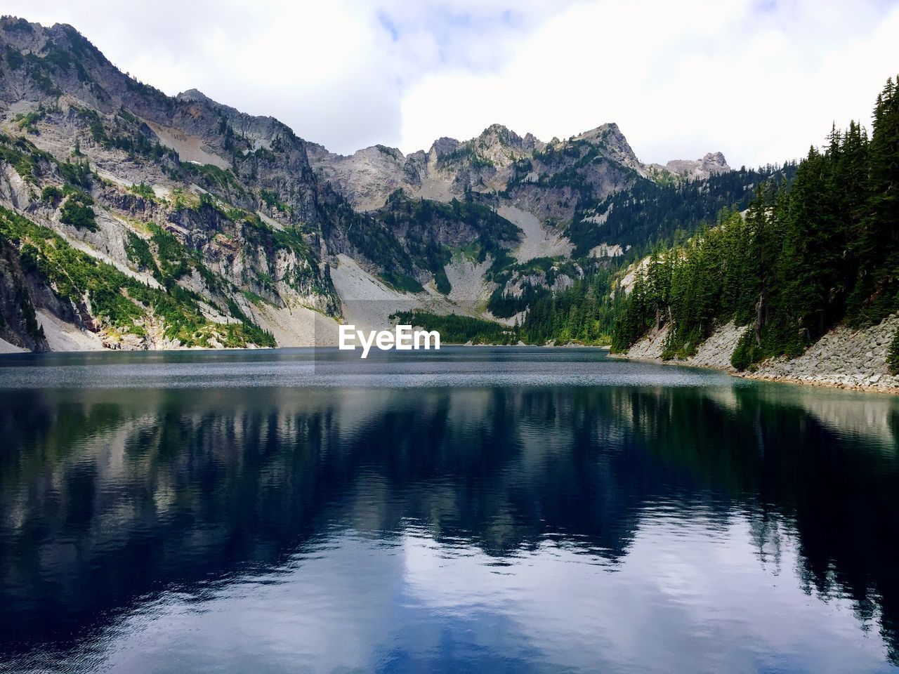 Scenic view of lake and mountains against cloudy sky