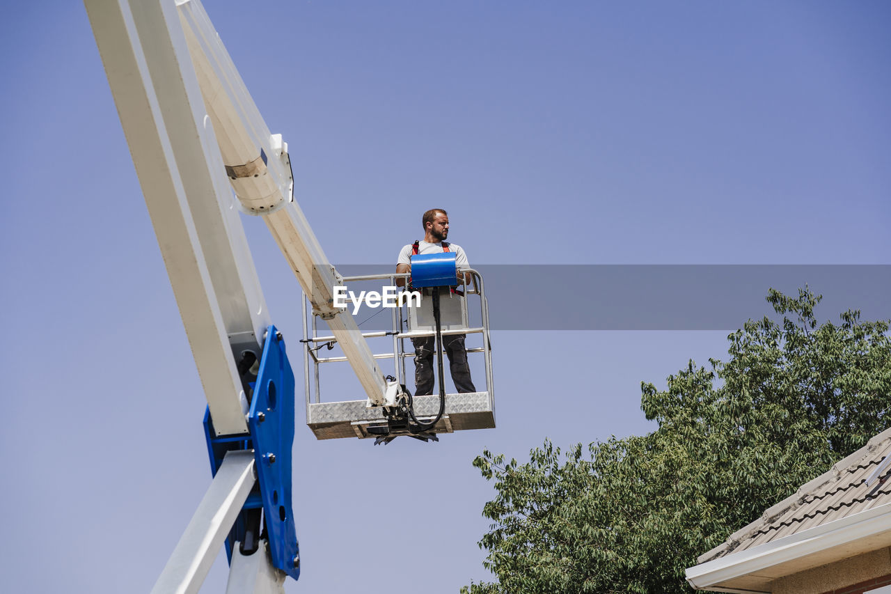 Engineer standing on hydraulic platform by roof