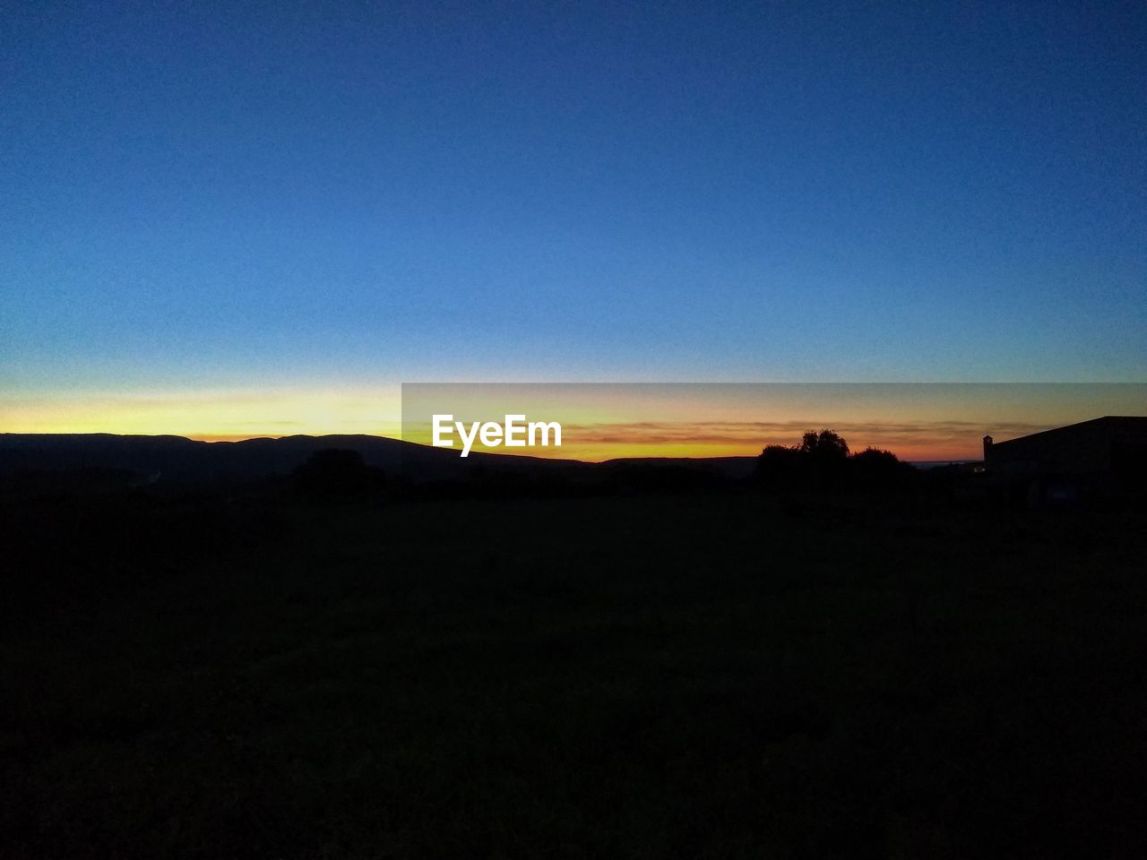 SCENIC VIEW OF SILHOUETTE LANDSCAPE AGAINST CLEAR SKY DURING SUNSET