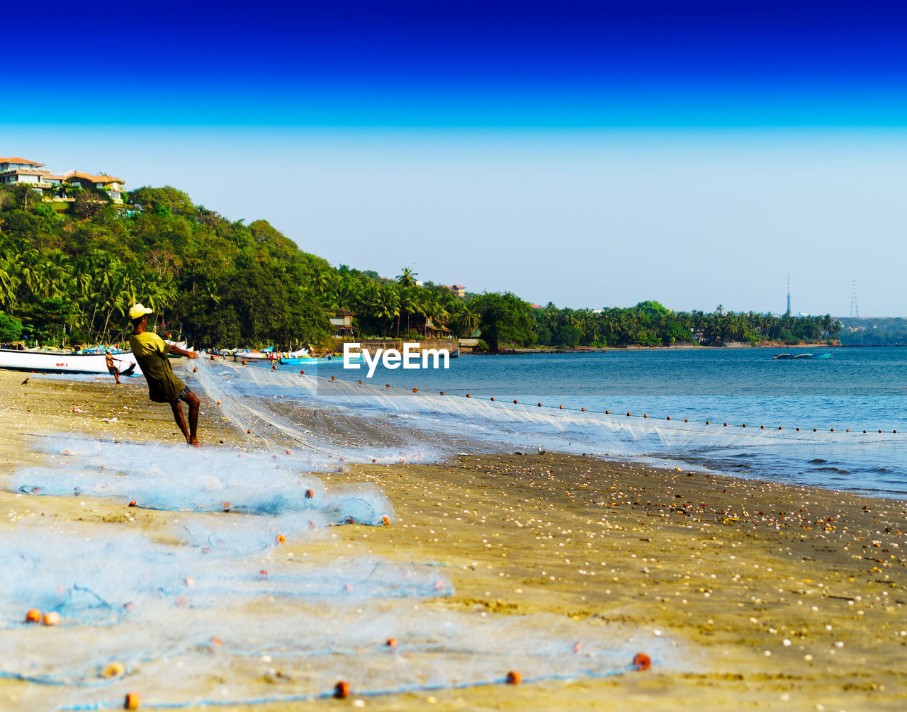 Fisherman casting net on sea shore