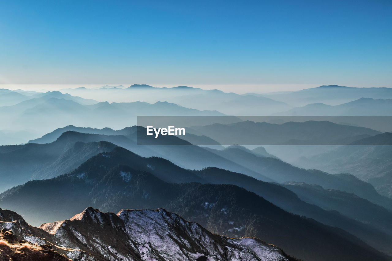 Scenic view of snowcapped mountains against clear blue sky