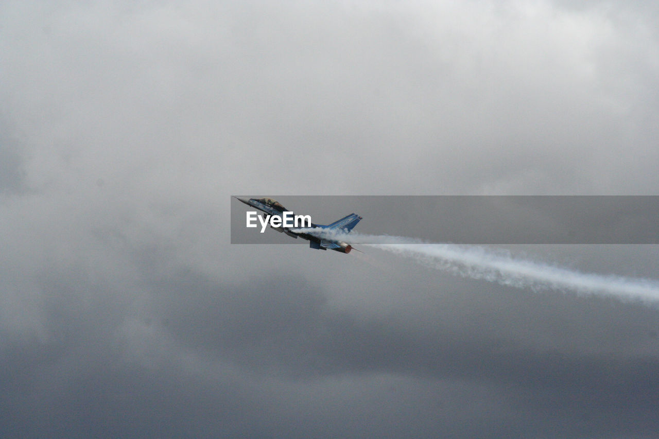 Low angle view of fighter plane flying in cloudy sky