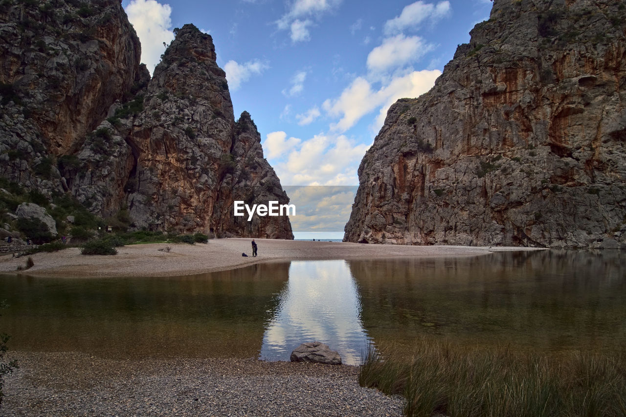 Rock formations by lake against sky