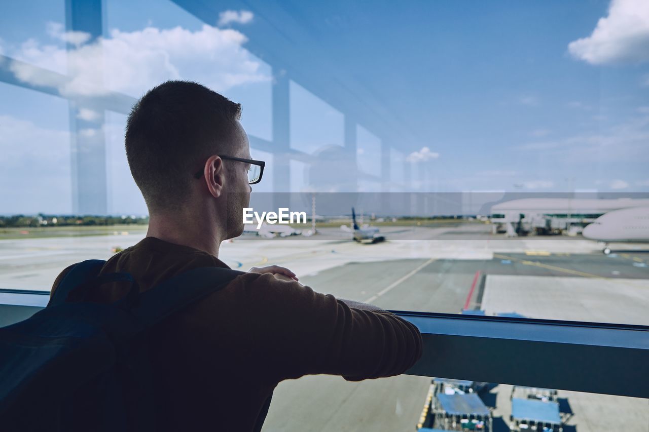 Man looking at airport runway through window