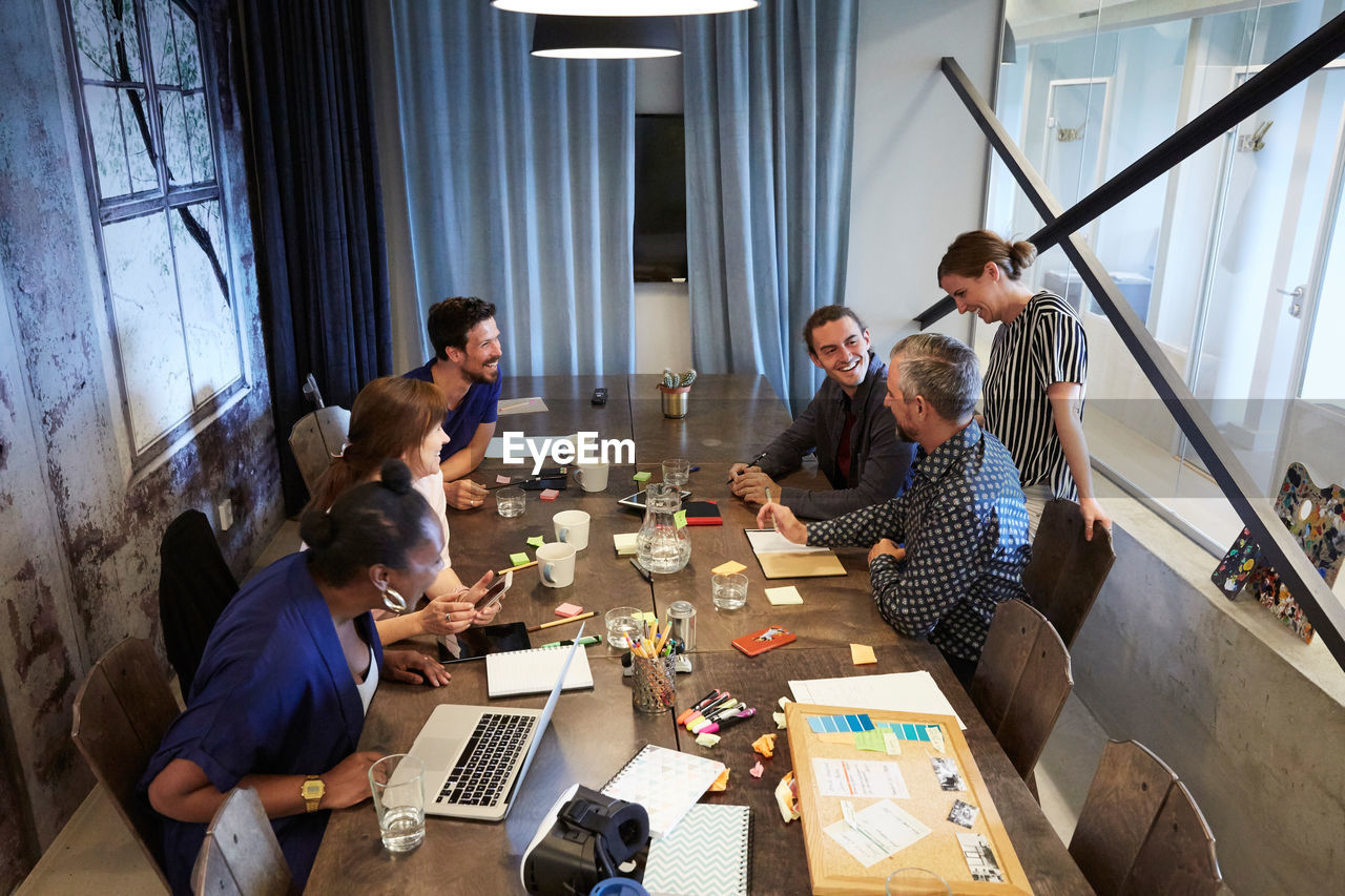 High angle view of colleagues discussing at conference table during meeting in office