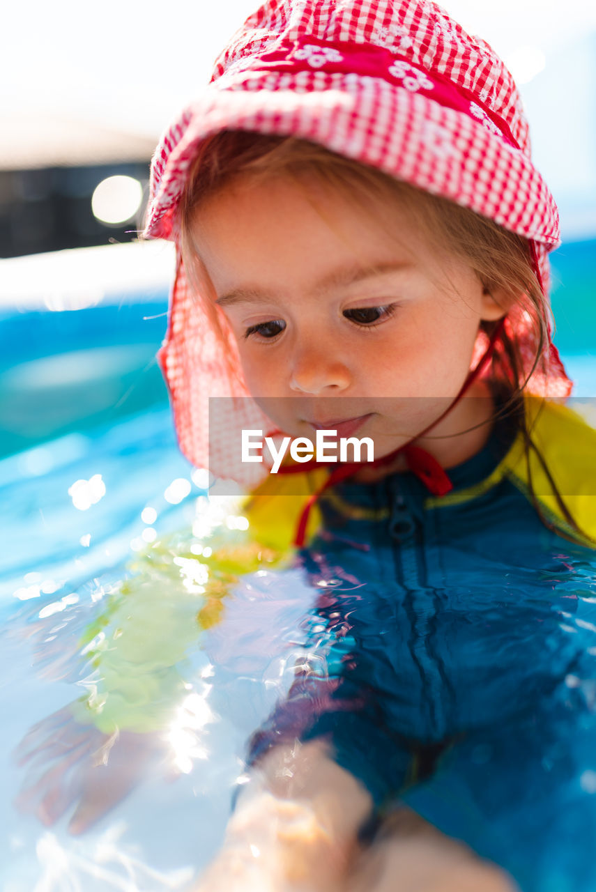 Child in inflatable swimming pool in backyard. proper sun protection for babys concept.