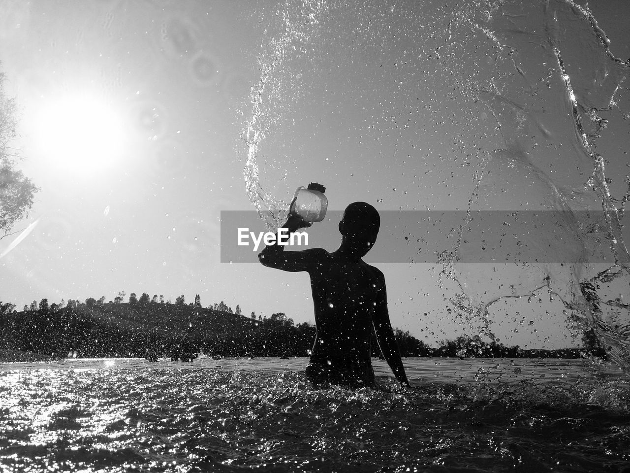 Silhouette man splashing water in river