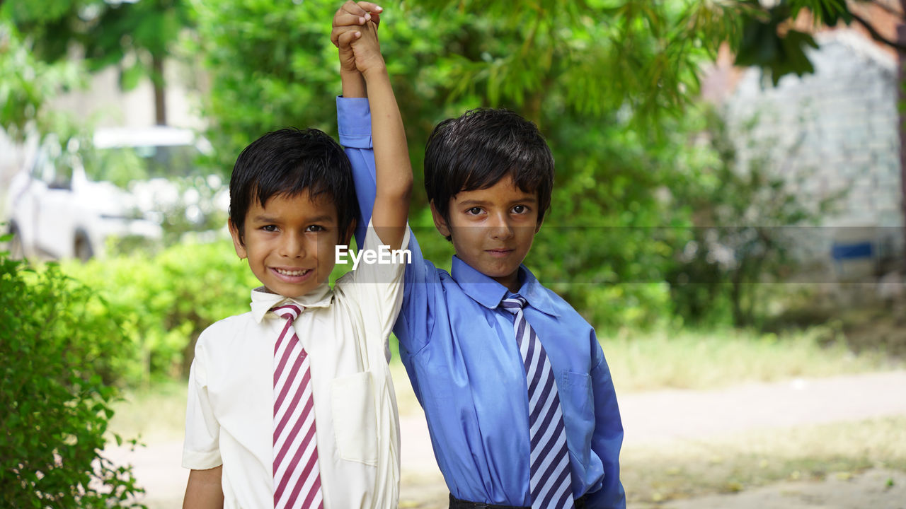 Portrait of happy cheerful indian school child or kids in uniform raising hand in the classroom