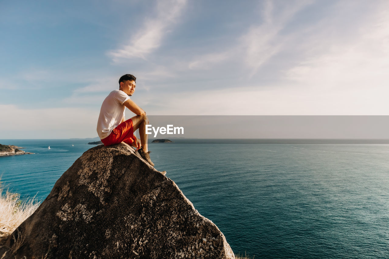 Man rest on the sea cliff rock after finish his hike trail.