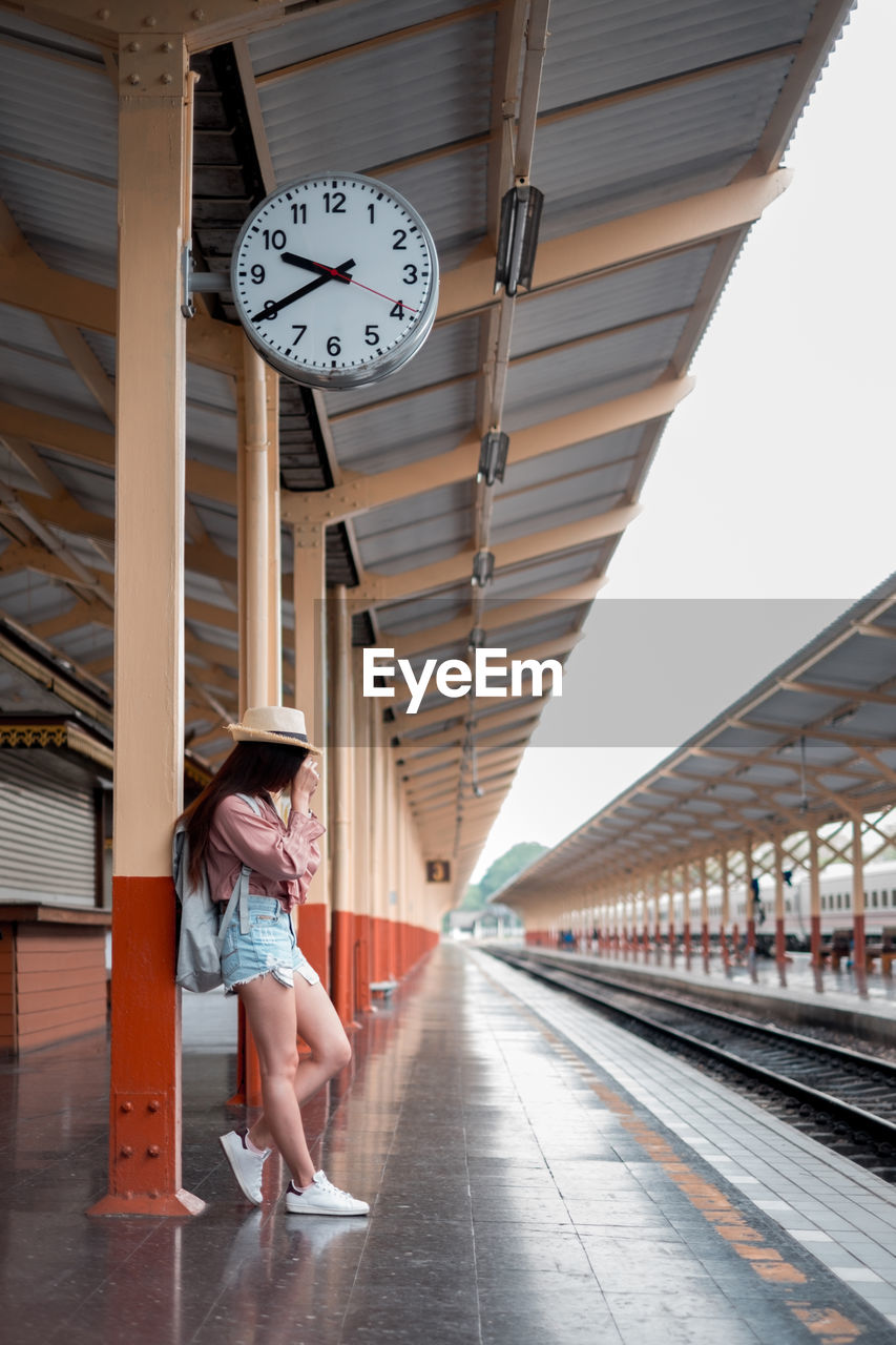 Woman leaning on railroad station platform