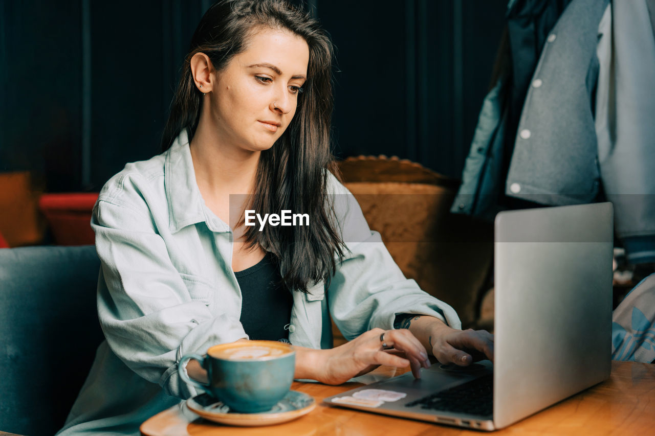 Young modern woman works in a cafe on a laptop.